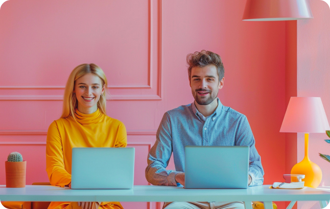 Two people working at laptops in a colourful office.